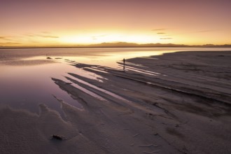 A solo traveler at a mesmerizing sunset in Salinas Grandes, Salta, Argentina, where the vast salt