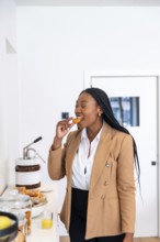 Businesswoman enjoying a delicious pastry while savoring the hotel breakfast buffet during a