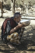 Ali drinking milk after milking one of his camels (camelus dromedarius), camel farm of Sheikh Ahmed