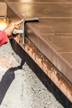 Construction Worker Using Stainless Steel Edger On Wet Cement Forming Coping Around New Pool
