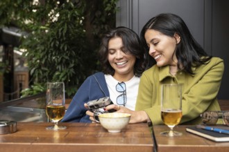 A joyful lesbian couple enjoys a sunny afternoon together, sharing moments with a vintage camera.