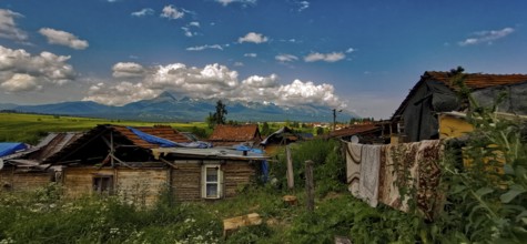 Rural scene with huts and mountains under a wide cloudy sky, atmospheric atmosphere, bright colors,