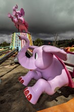 Pink elephant figures of a stopped carousel on a cloudy day, amusement park and carousel in Nuwara