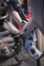 Cables being laid in a bicycle frame, hands with gloves working on it, Waldbike Manufaktur, bicycle