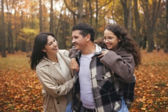 A cheerful family walks in an autumn forest, surrounded by vibrant foliage. They enjoy the crisp