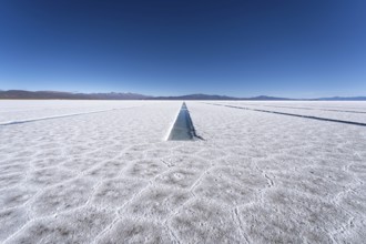 Endless white salt crust of Salinas Grandes and pool channels under a clear blue sky, with distant