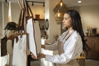 A woman carefully examines a large handbag displayed in a stylish, well lit bag store. The setting