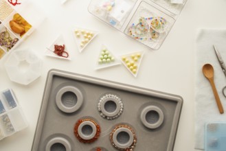 Top view of a creative jewelry making setup in a studio with tools like scissors, a wooden spoon,