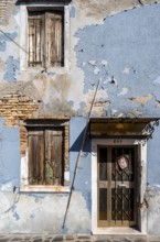 Dilapidated blue house facade with entrance door and windows, colourful houses on the island of