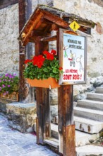 Flower-decorated signpost for cyclists and pedestrians, historic town centre, Grimentz, Val