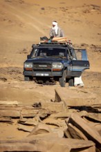 An off-road vehicle with people in traditional clothing stands in a vast desert landscape, Off-road