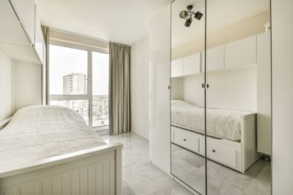 Bright, minimalist bedroom featuring a single bed, mirrored wardrobe and large window with