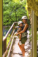 Mother carrying her son in a baby carrier while enjoying a hike through the scenic vintgar gorge