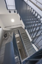 View from above of a modern staircase with metal railing that connects several floors, new Calw