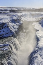 Large waterfall in a gorge in the snow, winter, sunny, backlight, spray, Gullfoss, Golden Circle,