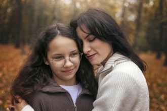 A touching moment of a mother and daughter embracing in an autumn forest. Surrounded by warm,