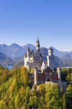 Neuschwanstein Castle surrounded by autumnal forests and mountains in the background, Schwangau,