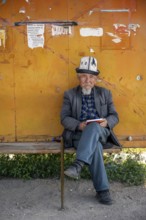 Local man with traditional hat waiting at a bus stop, Issyk-Kul region, Kyrgyzstan