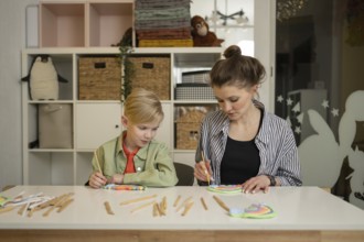A teacher guides a child through a fun art lesson. The room is filled with colorful supplies,