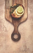 Salmon steak, fried, on a cutting board, top view, rosemary, lemon and lime, homemade, one serving,