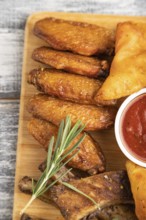 Set of snacks: nachos, chicken wings, fried ribs, bean tortillas on a cutting board on a gray