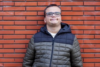 Man with an intellectual disability smiles warmly while leaning against a brick wall. His relaxed
