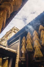 Spiral incense cones hang within the dimly lit interior of a Taoist temple in Macau, emitting