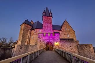 Atmospherically illuminated castle at night, access via a bridge, Spangenberg Castle