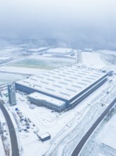 Large industrial plant in the snow, surrounded by roads, seen from the air, gives a sober winter