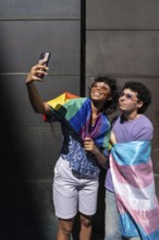 A joyful multiethnic LGBTQ+ couple takes a selfie wrapped in pride flags, celebrating love,