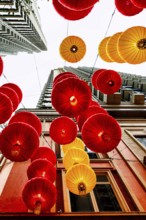 From below radiant red and yellow lanterns hang between skyscrapers in Hong Kong, celebrating