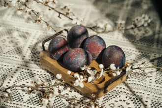 Cosmic-painted Easter eggs displayed on a rustic wooden tray, adorned with delicate white spring