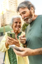 Vertical close-up of a happy senior couple walking using mobile phone in the city