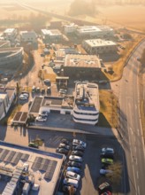 Aerial view of an industrial zone in sunny weather with parked cars and various buildings,