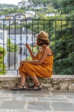 Portrait of a sitting tourist woman looking from a viewpoint at the city of Gjirokaster or