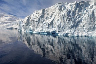 Fascinating iceberg formation with clear reflection in calm water under a blue sky, icebergs in the