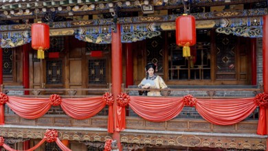 A woman in traditional Qing Dynasty attire stands on a beautifully decorated balcony in Pingyao,