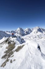 Ski tourer stretches his arms triumphantly into the air, summit happiness at the summit of the