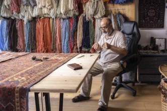 An Iranian master craftsman meticulously restores a carpet in his well-organized workshop in