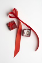 From above, a romantic Valentine's Day setup featuring a red ribbon arranged in a heart shape, with