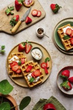 Rustic homemade waffles topped with fresh strawberries, yoghurt, and mint. Served on ceramic