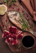 Fried dorado fish, with spices and herbs, on a wooden board, pomegranate sauce, close-up, no people