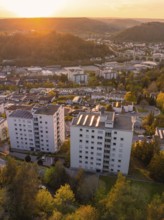 Tall buildings in a cityscape at sunset, surrounded by nature and hills, Nagold, district of Calw,
