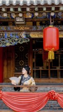 A woman dressed in traditional Qing Dynasty attire holds a fan while standing on a decorated