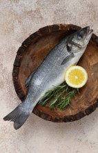Fresh, raw sea bass fish, in a wooden plate, top view, no people.