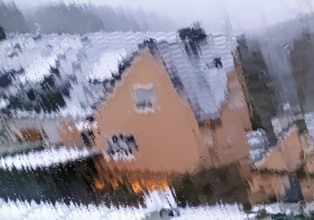 Continuous sleet on a window pane with an unclear view of a house in winter, Witten, North