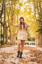 Portrait of a beautiful woman in autumn next to a forest in nature making a video call