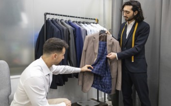 A tailor assists a customer in selecting a suit in modern store. The tailor shows the inner lining