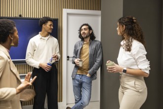 Group of colleagues in a contemporary office setting, engaged in a casual conversation during a