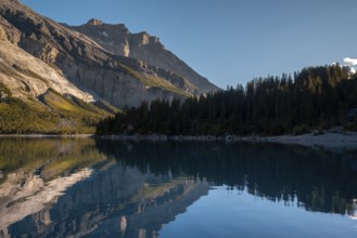 Tranquil lake Oachinensee in Switzerland reflects the majestic surrounding mountains and lush